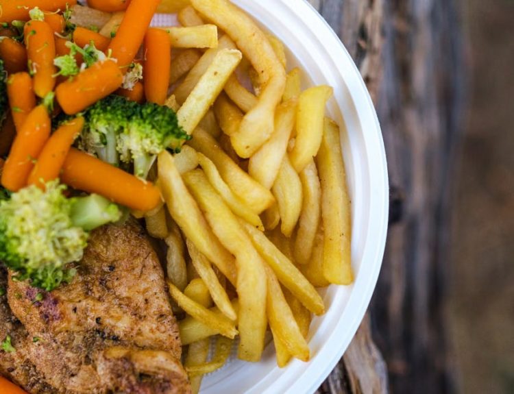 Delicious chicken dinner with broccoli, carrots, and fries on a plate.